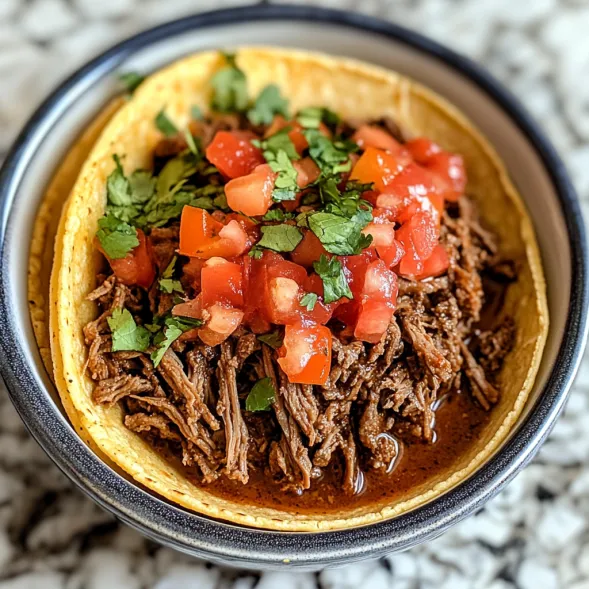 A bowl of beef with tomatoes and lettuce.