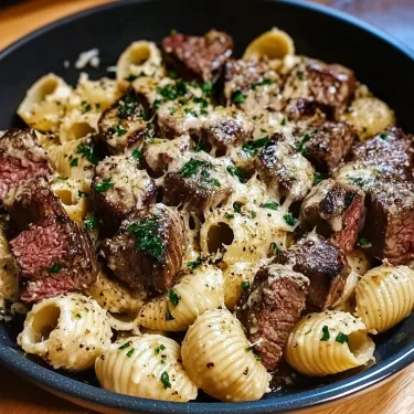 A bowl packed with cheesy pasta and steak pieces.