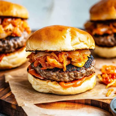 Two hamburgers with onions and ketchup.