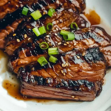 Steak topped with chopped green onions on a white plate.