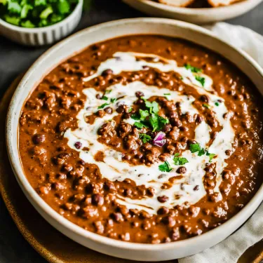 A spoon in a bowl filled with dal makhani.